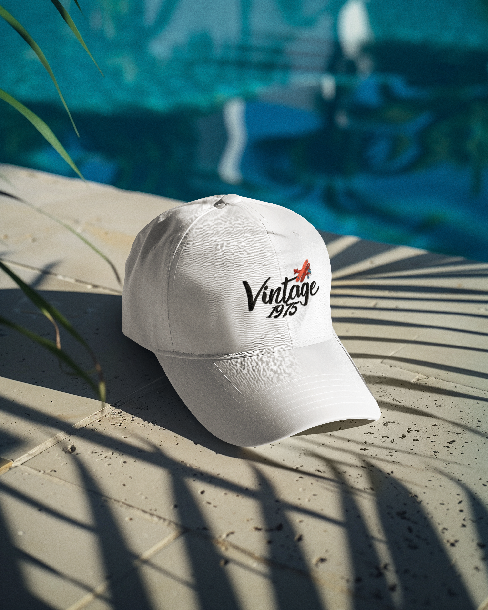 White cap with 'Vintage 1975' text on a stone surface near a pool.