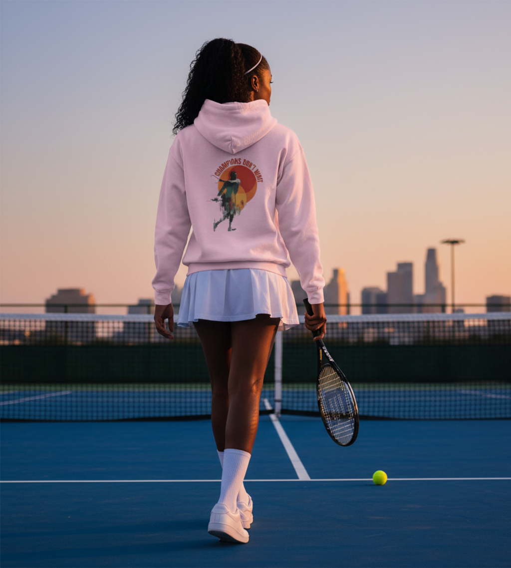 Person on a tennis court wearing a hoodie with a graphic design, holding a racket and a ball, with city skyline in the background.